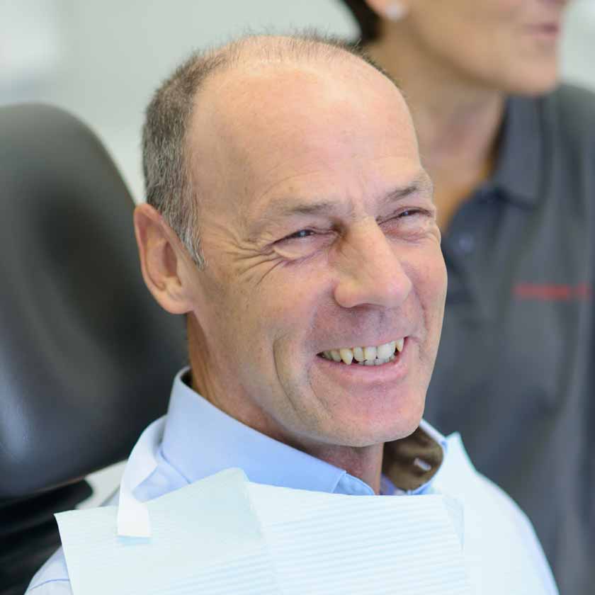 Lächelnder Patient im Gespräch zu den Möglichkeiten einer Schnarchschiene.